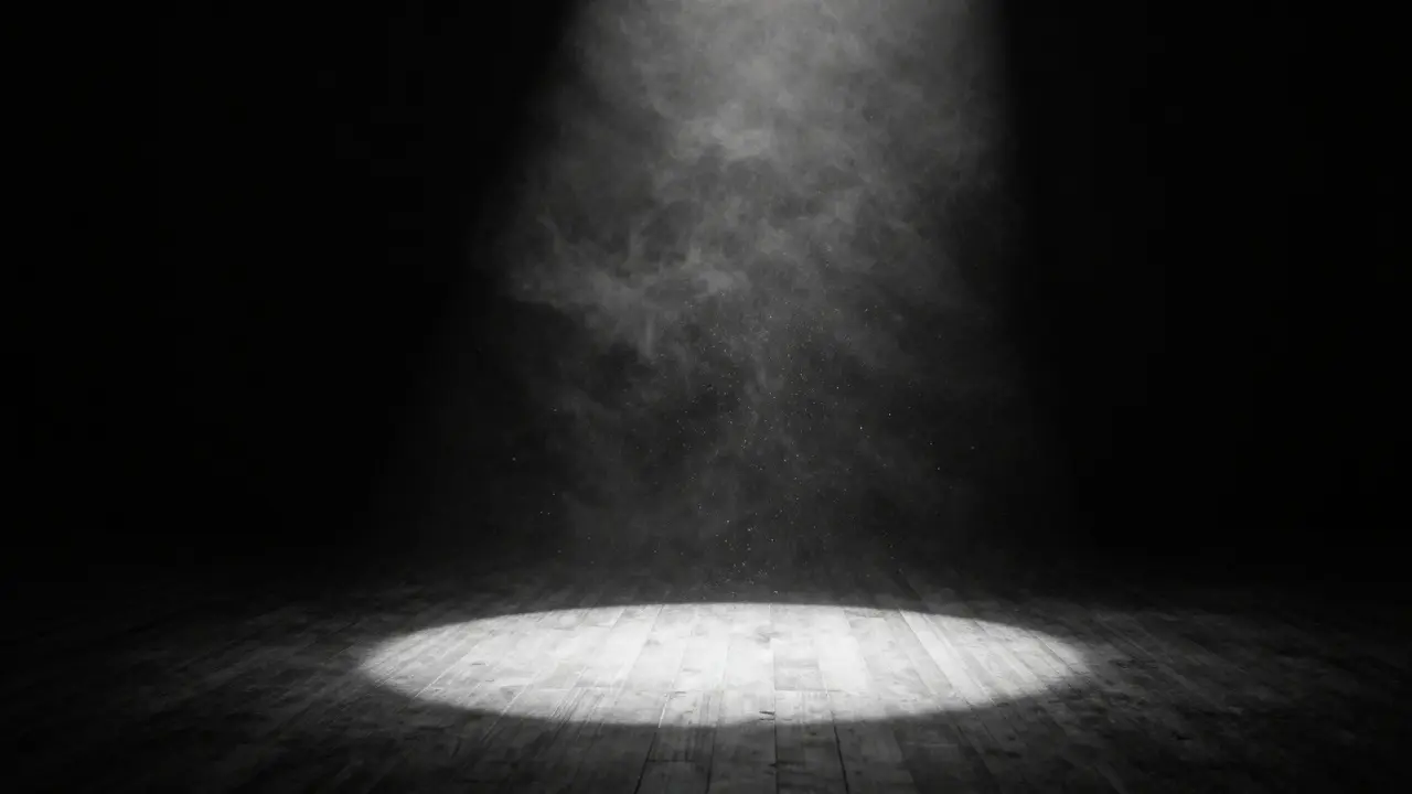Dramatic spotlight beam illuminating dust on a dark stage floor.